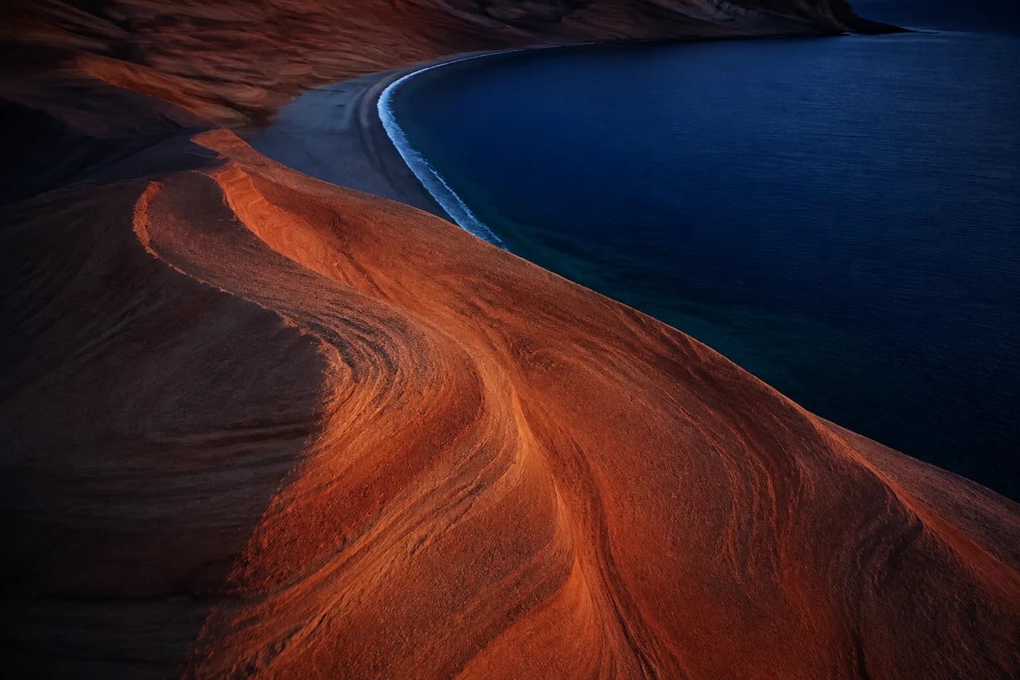 Pale sand dunes beside turquoise water; a sample media image
